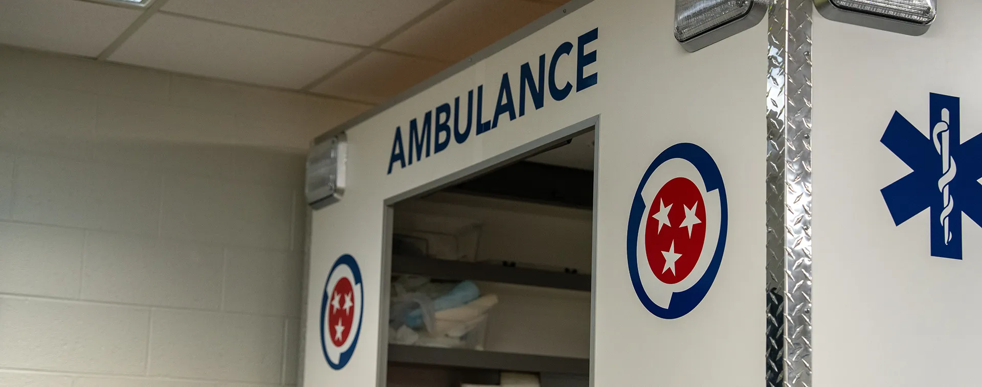 Ambulance training simulator with Tennessee emblems and the word &ldquo;AMBULANCE&rdquo; displayed above an open compartment.